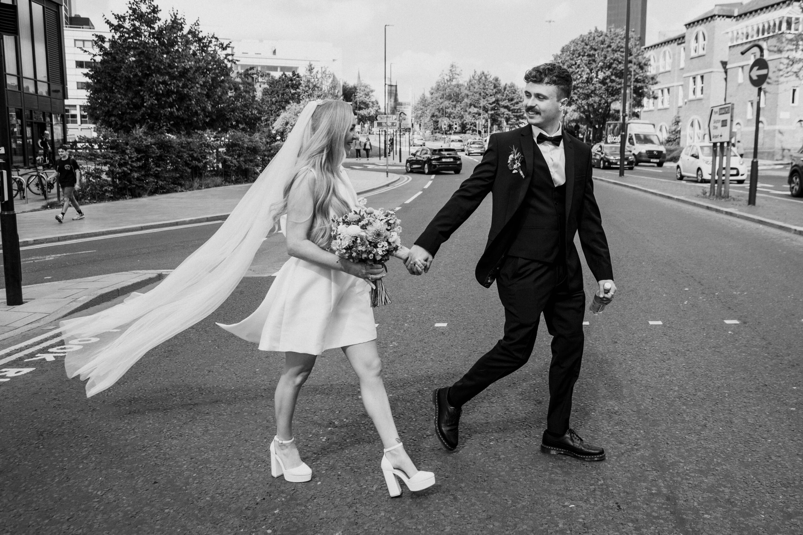 a couple cross the road in leeds city centre after getting married at leeds civic hall