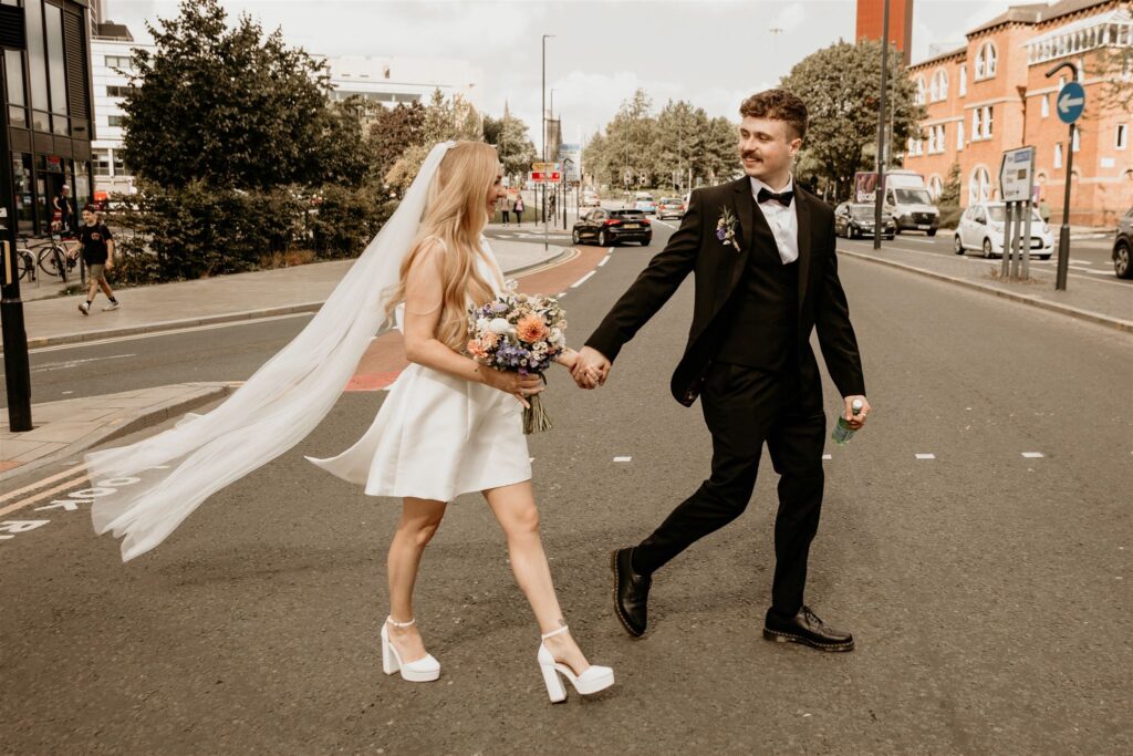 Documentary-style wedding photography of the bride and groom walking through the streets hand in hand 