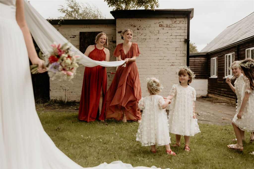 Documentary-style wedding photography of the bridesmaids holding the brides veil