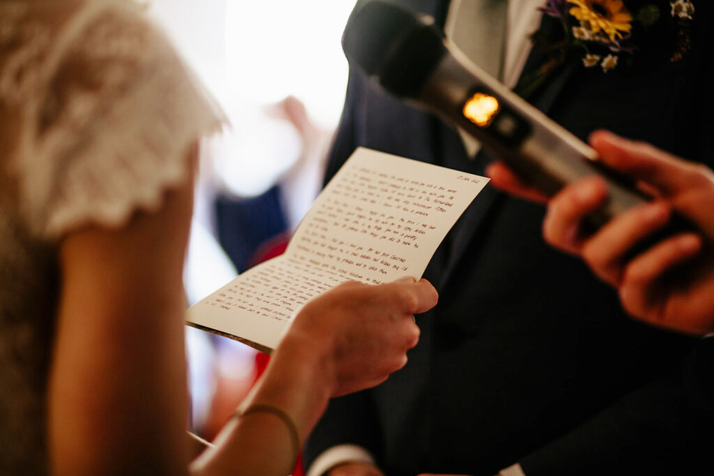 a bride holds her wedding vows as she reads them to the groom 